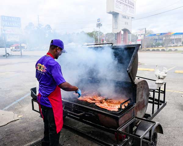 Person smoking ribs on a BBQ smoker at True BBQ in Columbia, SC.